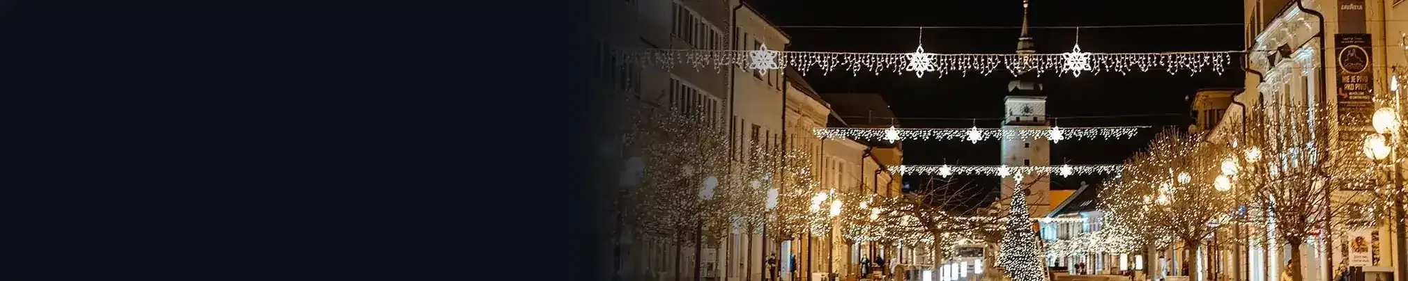 Street at night with Christmas lights across the street and on lamp posts