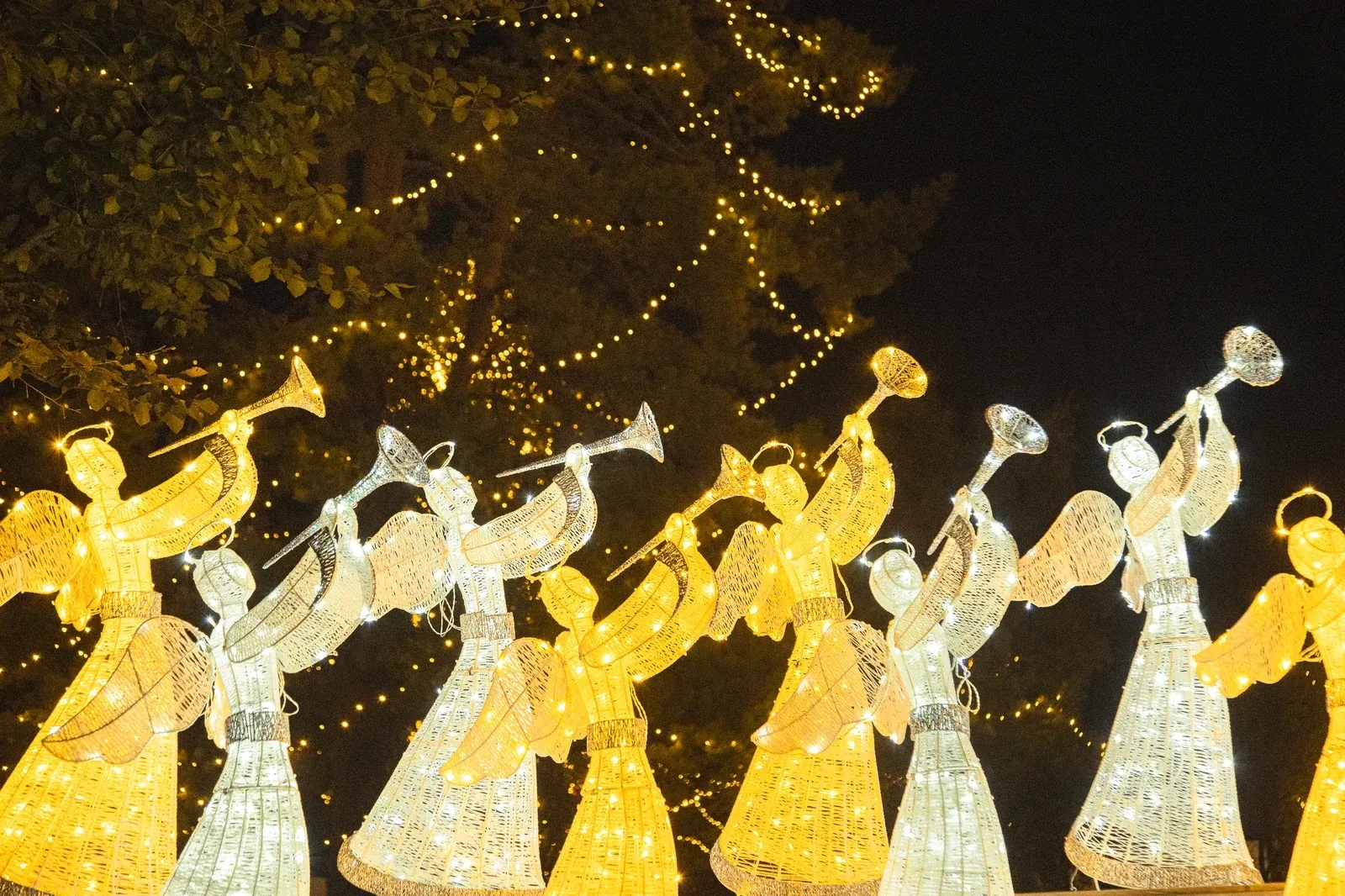 A row of warm white LED angels with trumpets, 122 cm, in a night-time light park at Gödöllő palace, 2025